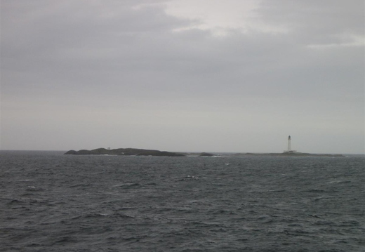 Rock way out at sea with lighthouse attatched