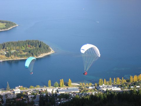 Two tandem paragliders decending over the lake.
